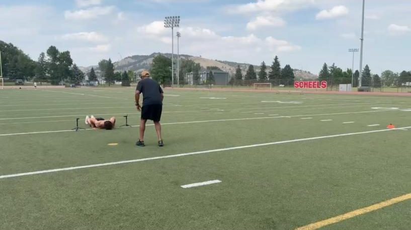 Coach running an athlete through a drill on the turf